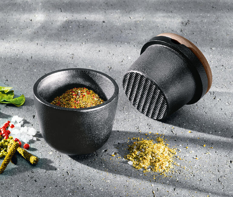 Mortier en fonte avec des épices sur la table.