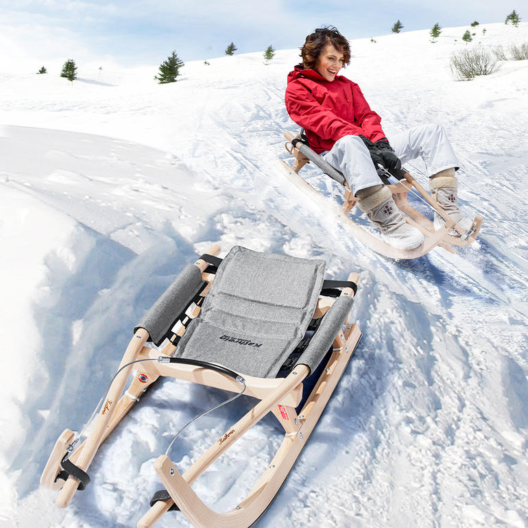 Enfant glisse sur une luge en bois dans la neige.