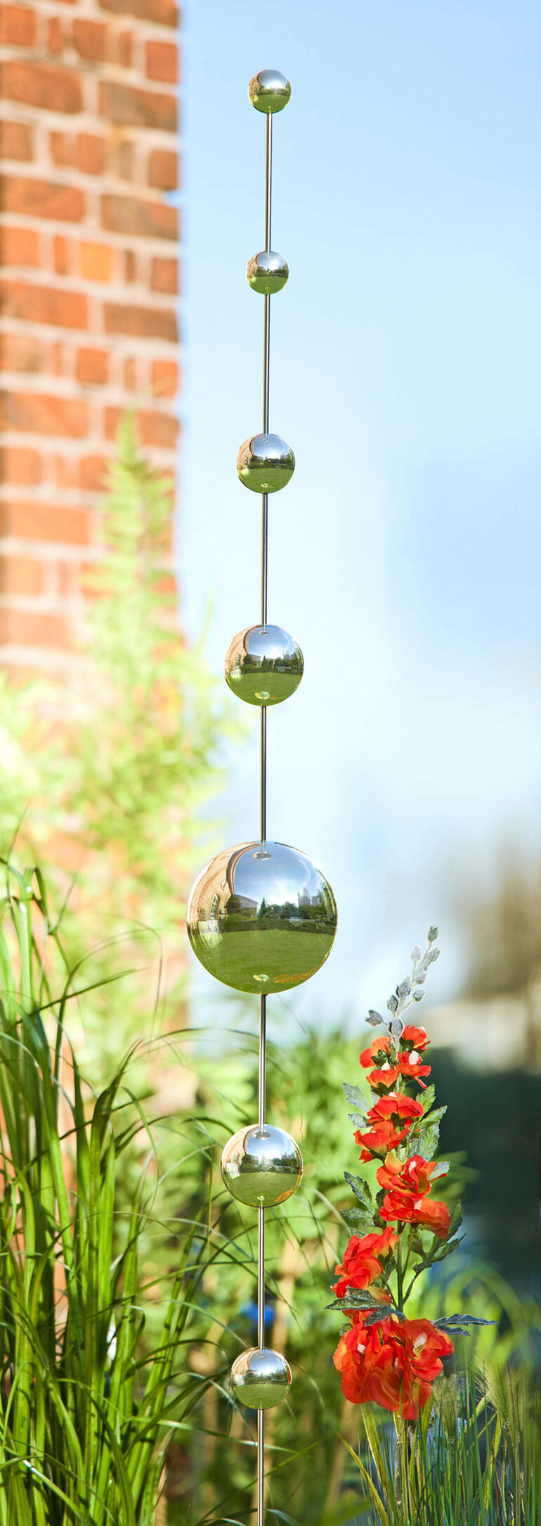 Décoration en métal avec des boules de différentes tailles, parmi des plantes vertes