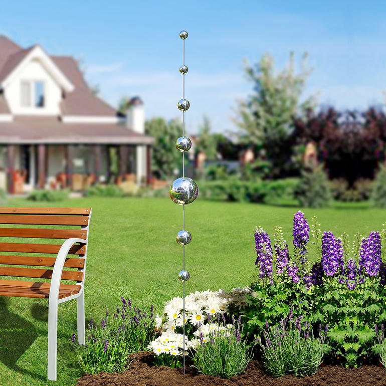 Jardin avec des bâtons en forme de boule entre les fleurs.