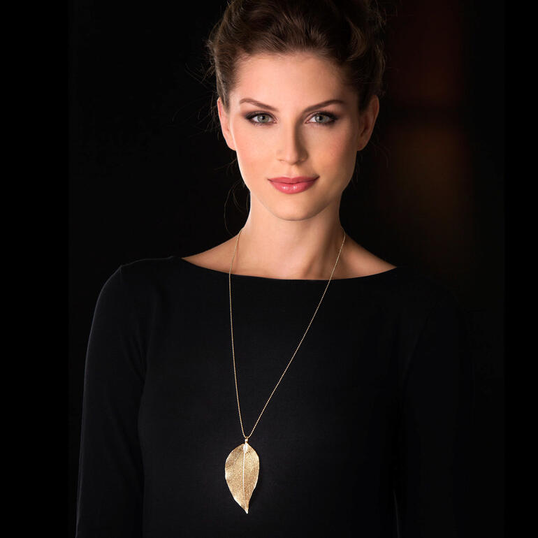 Or Femme portant une chaîne Bodhi en feuille dorée sur un fond noir.