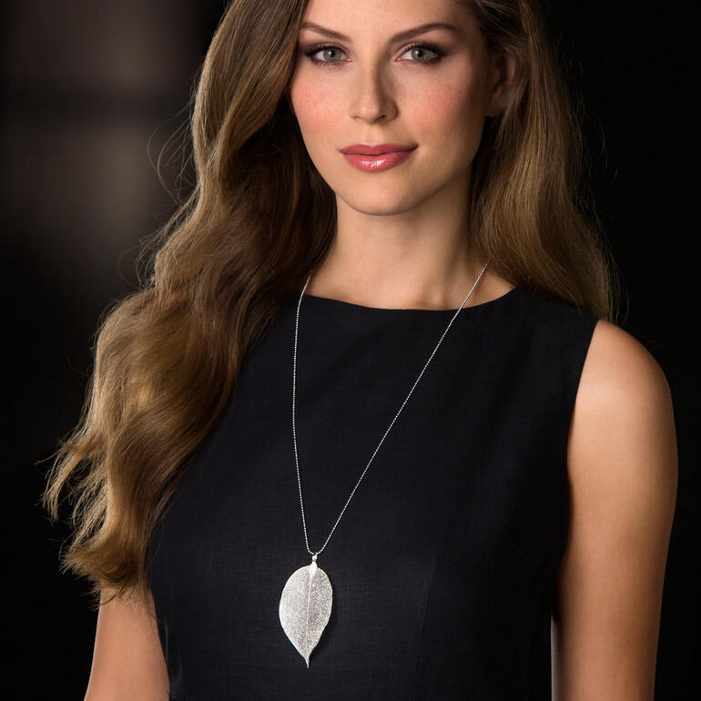 Femme portant une chaîne Bodhi en feuille argentée sur un fond noir.