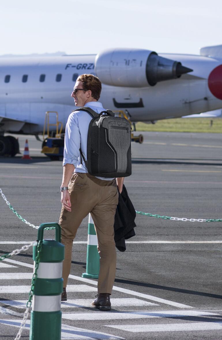 Homme avec un sac à dos à l'aéroport devant un avion.
