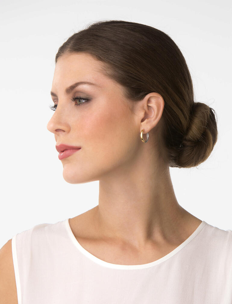 Femme avec des créoles bicolores regardant latéralement vers l'objectif.