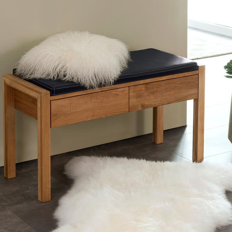 Banc en chêne avec coussin sur un tapis duveteux.