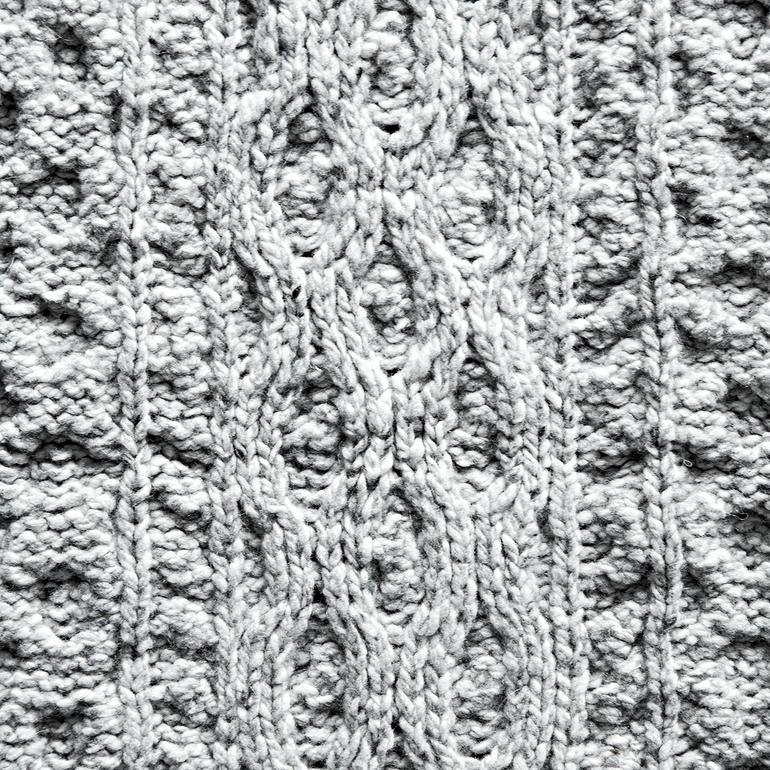 Plaid en tricot Aran IrelandsEye Gros plan du motif tricoté d'un plaid gris.