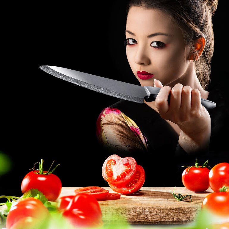 Personne avec un couteau en céramique zirconia coupant des tomates fraîches sur une planche à découper.