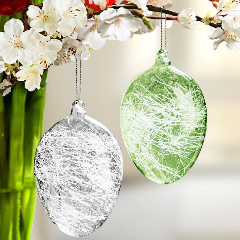 Oeufs de Pâques en fil de verre transparents et verts, décorés de branches fleuries.