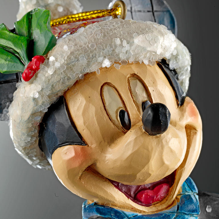 Effet sculpté d’une seule pièce de bois. Détails de Mickey Mouse avec un bonnet de Noël et une écharpe verte, visage joyeux.