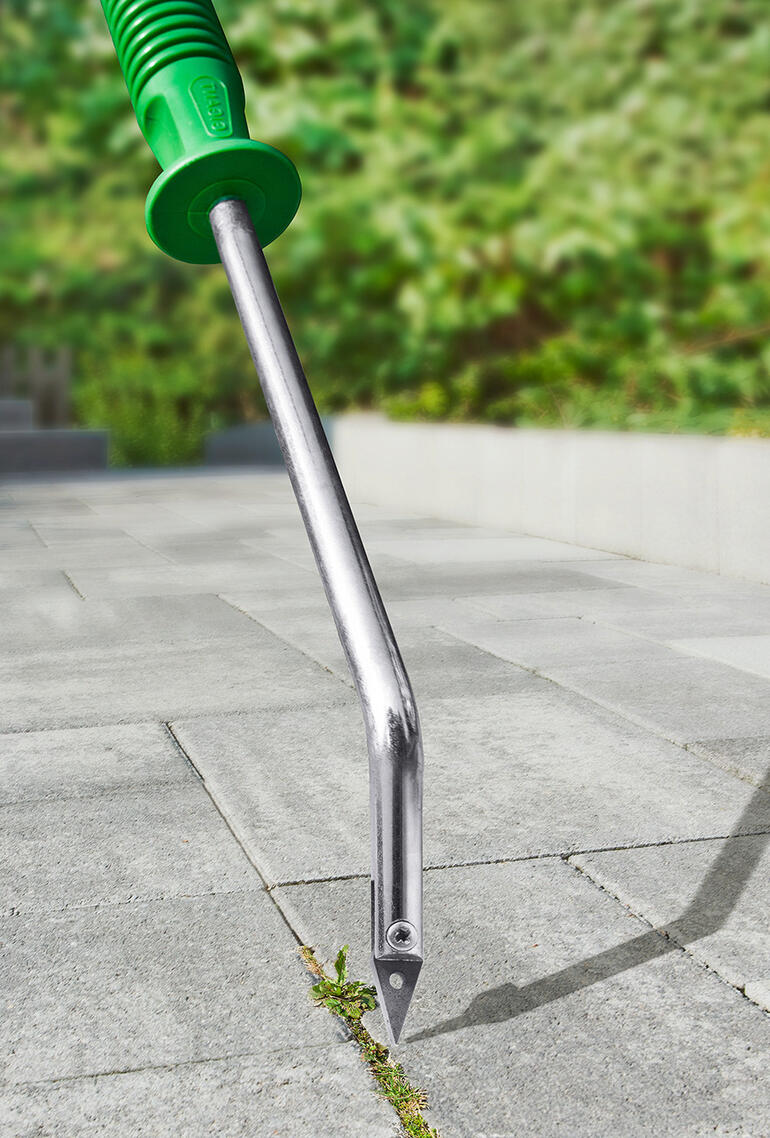 Grattoir à joints avec coupe en V sur un chemin pavé.