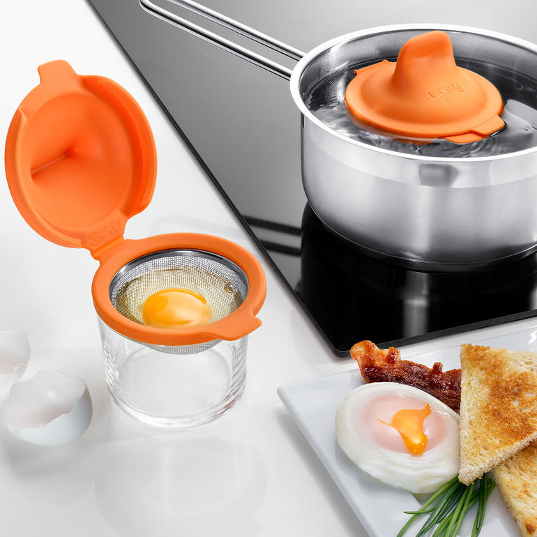 Pocheurs à œufs, lot de 2 pièces Pocher à œufs orange près d'une casserole d'eau sur la cuisinière.