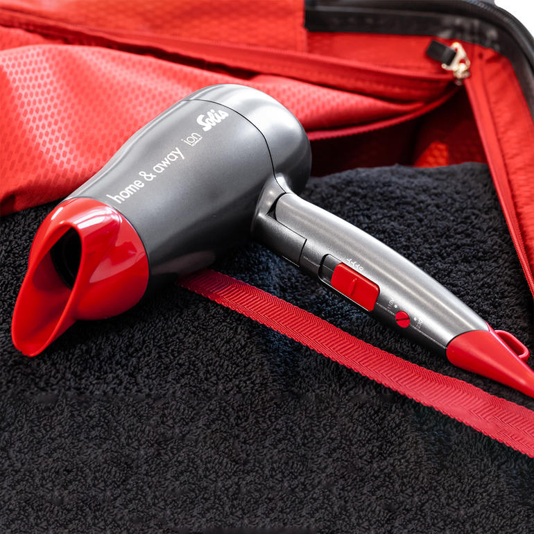 Sèche-cheveux compact Solis avec poignée rouge dans les bagages.
