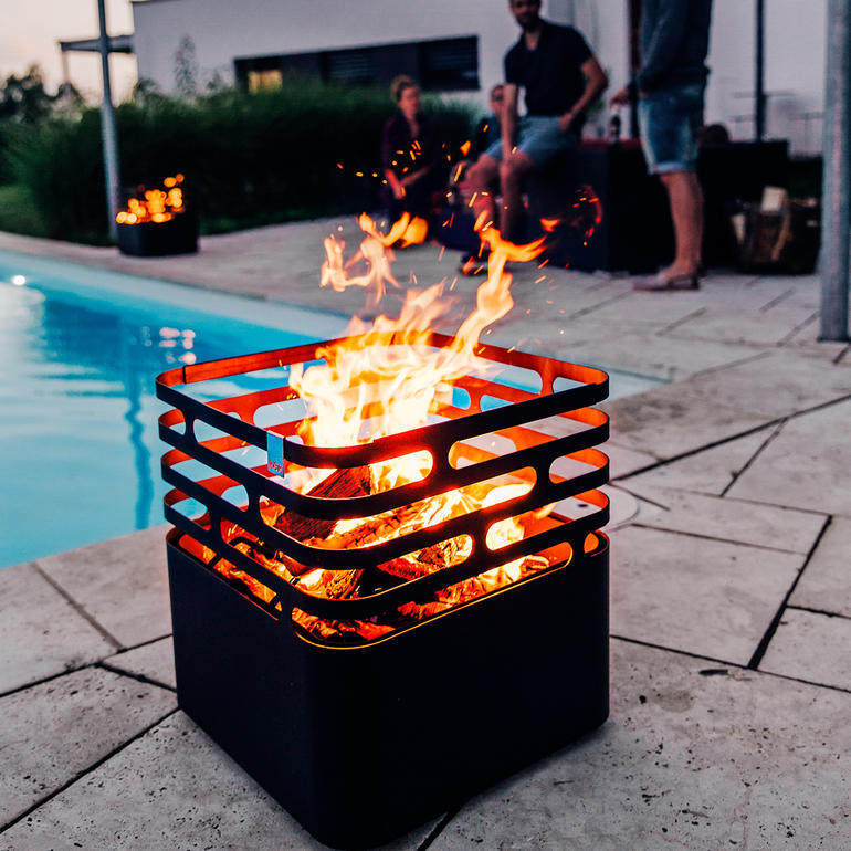 Cube de feu avec des flammes, des gens en arrière-plan.