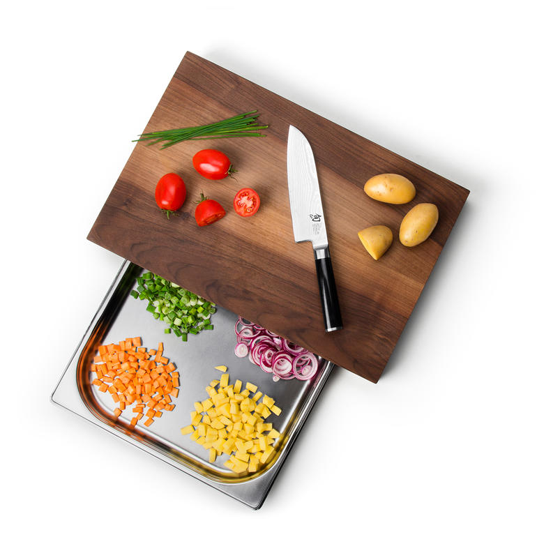 Planche à découper professionnelle à coupelle de récupération Planche à découper professionnelle vue de dessus avec légumes et un couteau de cuisine.