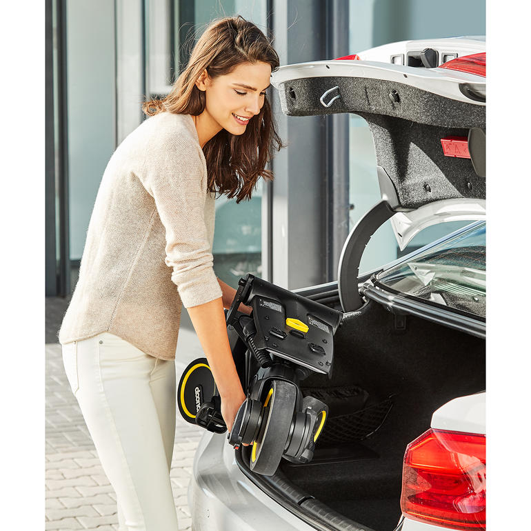 Se plie en quelques secondes au format d’un bagage à main. Femme soulevant le tricycle pliable du coffre d'une voiture.