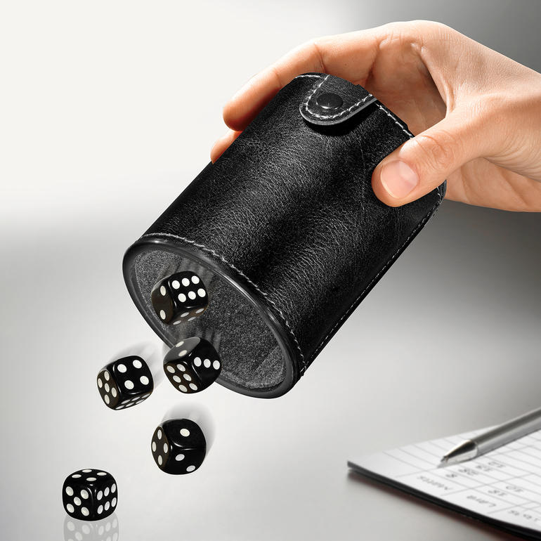 Main lançant les dés avec le gobelet à dés sur la table.