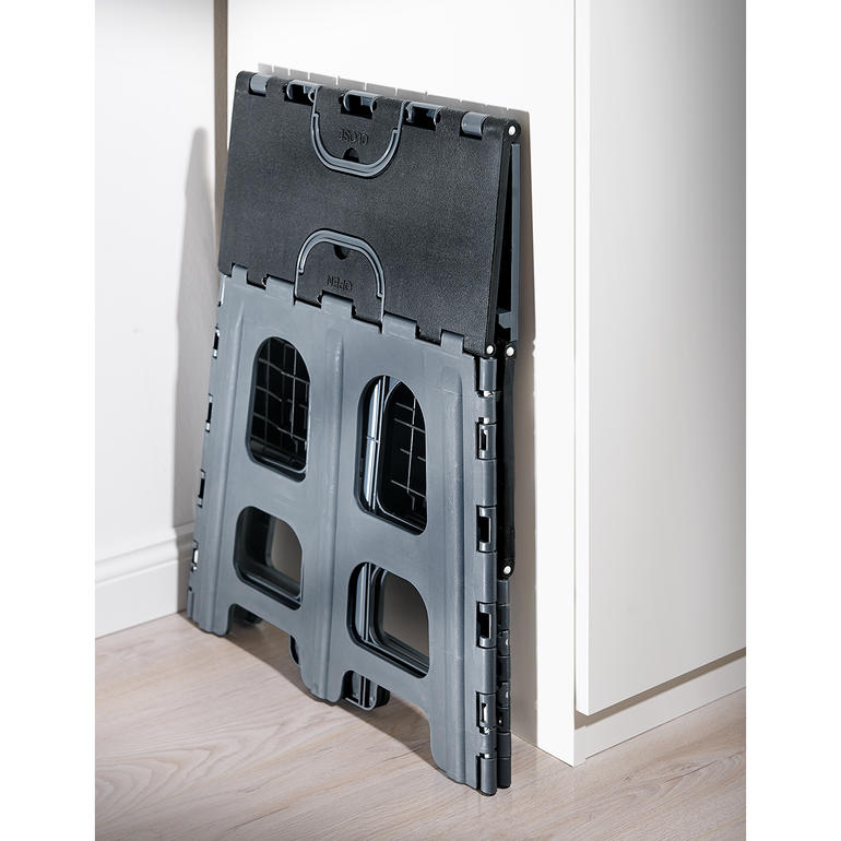 Replié, il ne mesure que 5 cm d’épaisseur pour un rangement facile. Escabeau pliable à deux niveaux replié contre un mur.