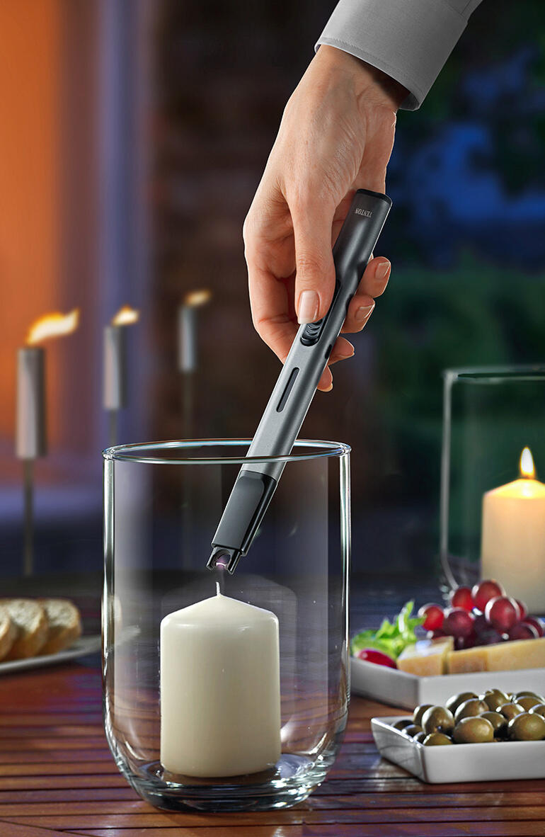 Main utilisant un allume-cigare pour allumer une bougie