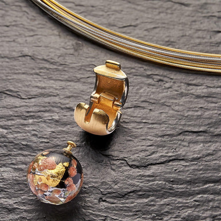 Clip et perle interchangeable en verre de Murano sur fond noir.