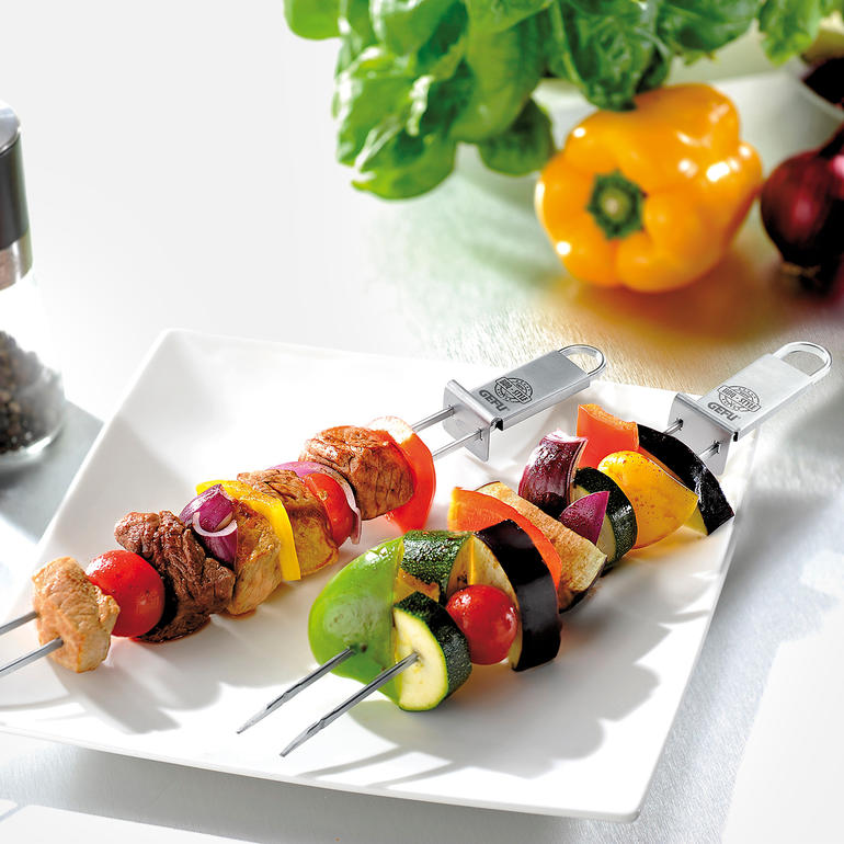 Brochettes doubles avec des légumes colorés et de la viande sur une assiette blanche