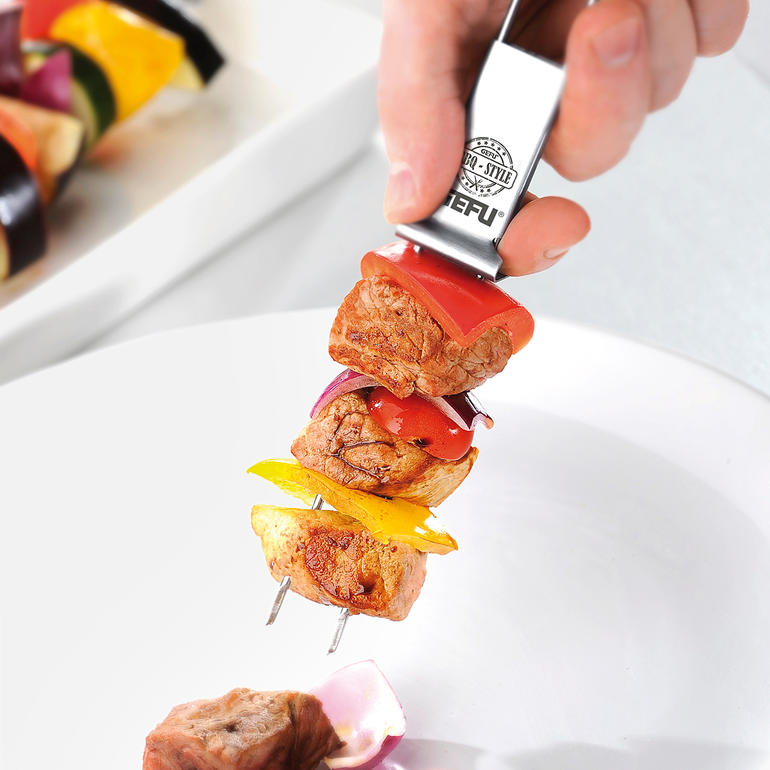 Main avec une brochette double garnie de légumes et de viande