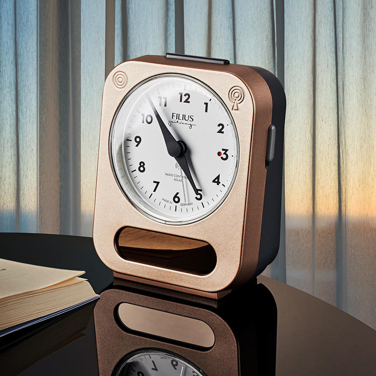 Réveil solaire radio avec un cadran blanc et un boîtier brun sur une table