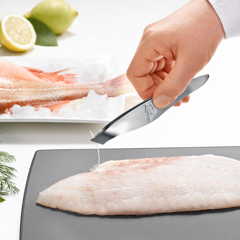 Main retirant une arête avec une pince à arêtes KAI.