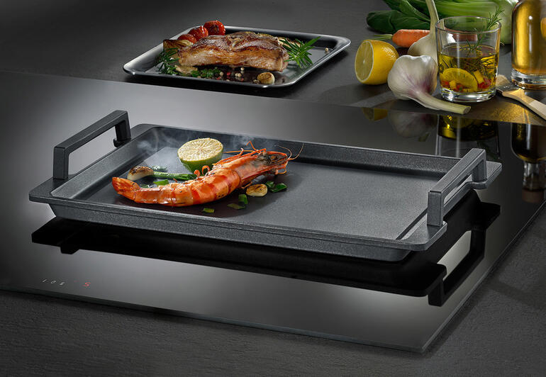 Plaque Teppanyaki avec crevettes et légumes sur une plaque de cuisson.