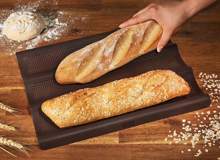 Tapis de cuisson en silicone pour baguette avec deux baguettes fraîchement cuites.