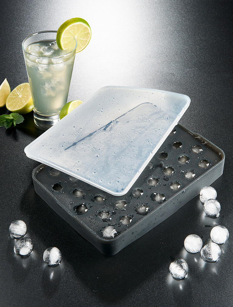 Moule à boules de glace avec des glaçons congelés et une boisson.