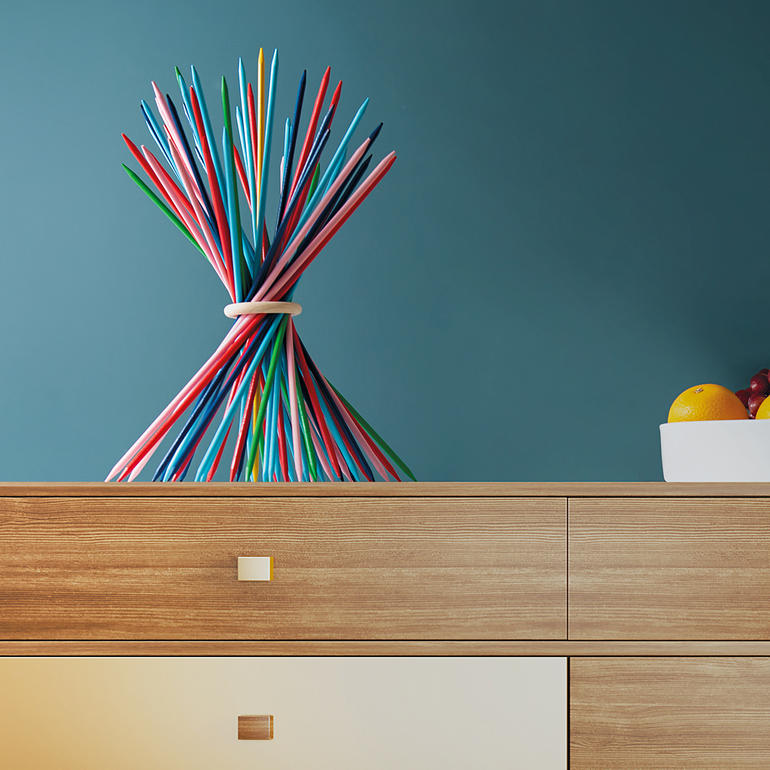 Bâtons XXL colorés disposés artistiquement sur une table en bois.