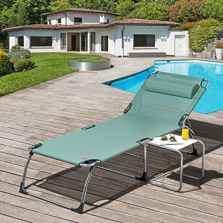 Chaise longue XXL en vert sur une terrasse en bois près d'une piscine.