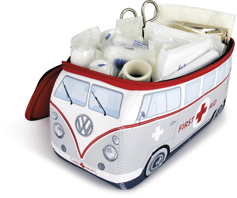 Contient une trousse de premiers soins complète conforme à la norme DIN : bandages, ruban adhésif, ciseaux, lingettes humides, gants de protection, couverture de survie ... Trousse de premiers secours VW ouverte avec le contenu sur fond blanc.