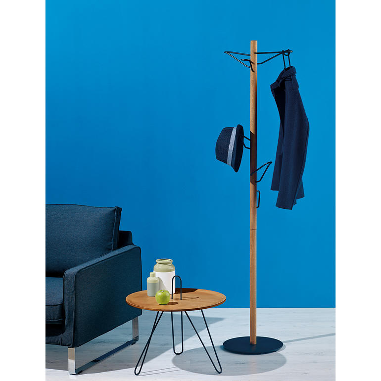 Portemanteau debout en bois avec une veste et un chapeau dans une pièce moderne.