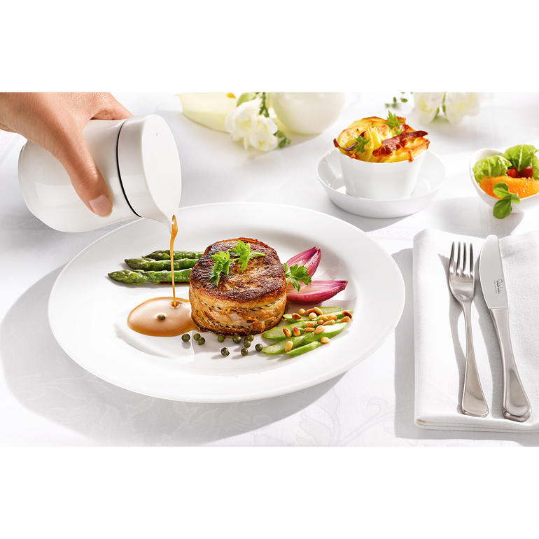 Femme sert la sauce avec une saucière thermique sur une assiette.