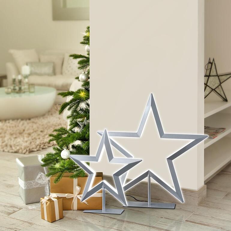 Étoile LED Deux étoiles LED à côté d'un sapin de Noël dans une pièce lumineuse.