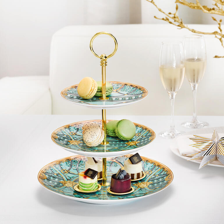 Etagère Versace 'La Scala del Palazzo' avec des macarons colorés et des desserts.
