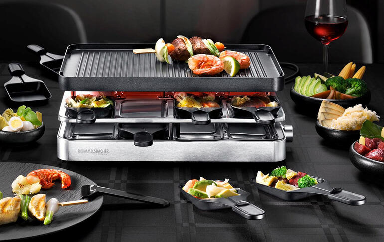 Raclette combinée RC 1400 avec différentes légumes sur la table.