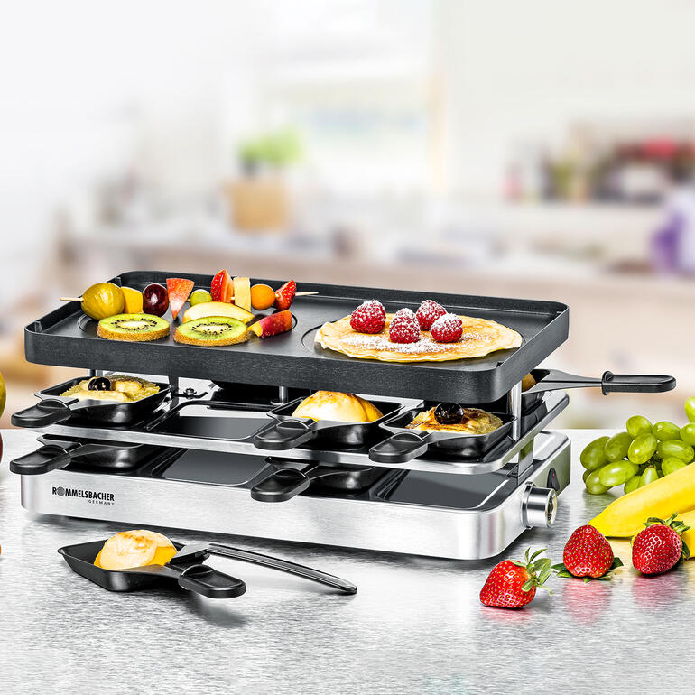 Raclette combinée RC 1400 avec des fruits frais et des crêpes sur la table.