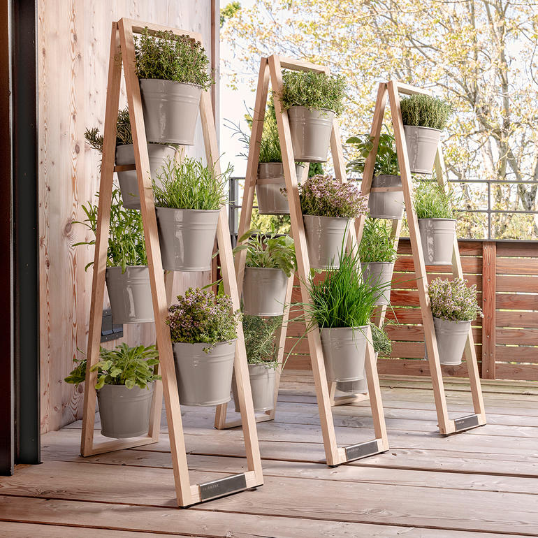 Trois échelles à plantes en bois avec des pots à l'extérieur sur une terrasse en bois