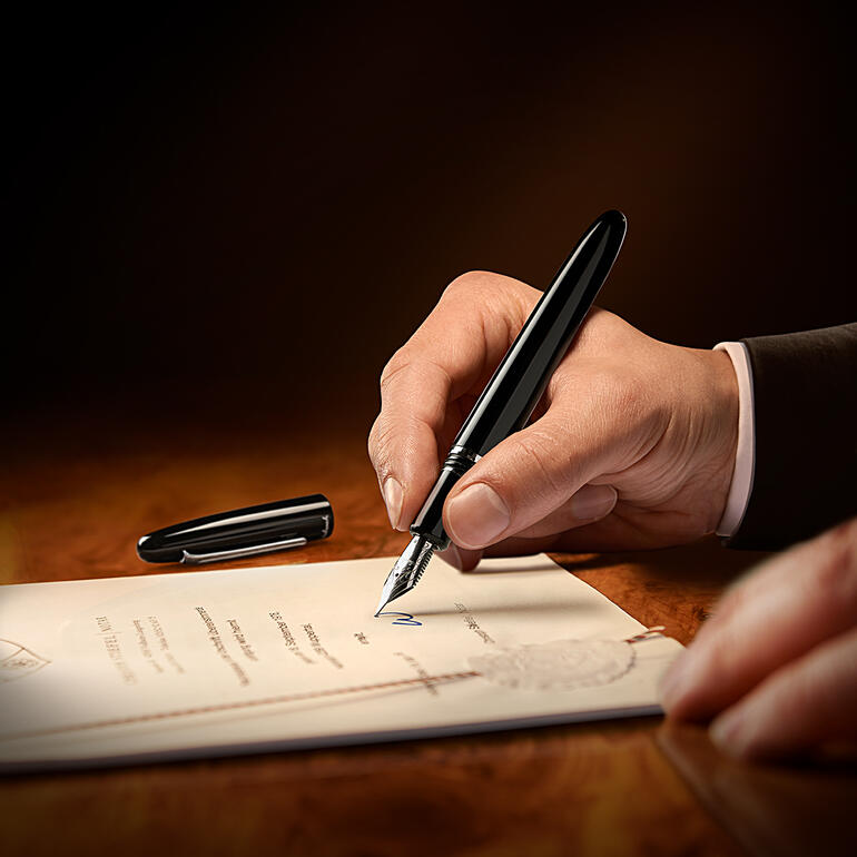 Stylo Esterbrook dans la main d'un homme écrivant sur un document.