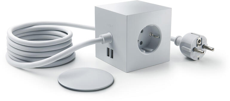 Cube de prise design gris clair avec câble et prise sur une table.