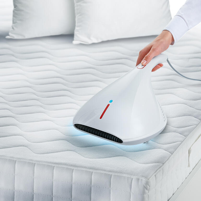 Aspirateur hygiénique UV-C passant sur un matelas pour désinfecter la surface.