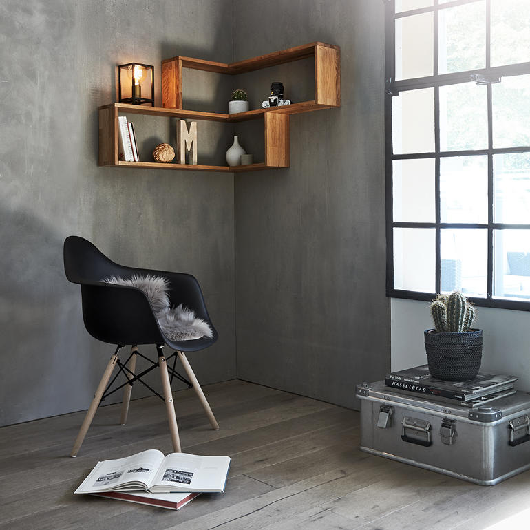 Étagère d'angle murale en bois avec des objets décoratifs et une chaise noire dans une pièce.