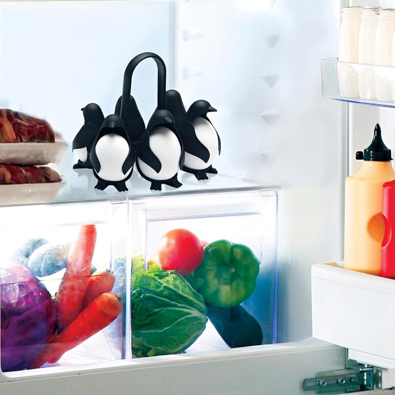 Porte-oeufs en forme de pingouins dans le réfrigérateur sur une étagère en verre.