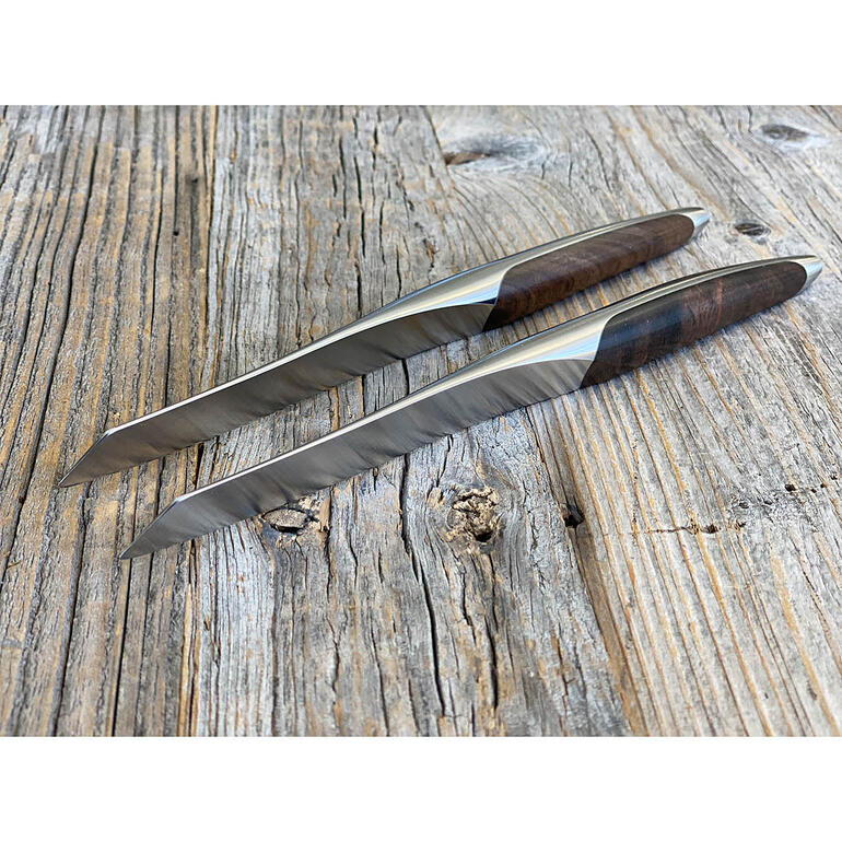 Deux couteaux à steak avec un manche en bois sur une surface en bois