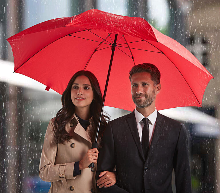 Couple sous un parapluie rouge sous la pluie.