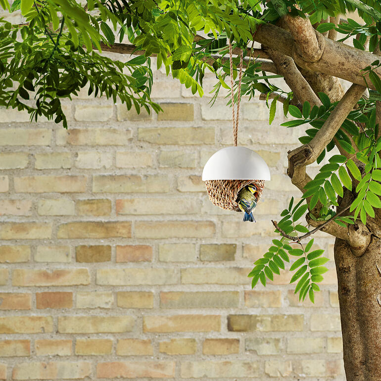 Nid d'oiseau en matériau doux suspendu à un arbre.