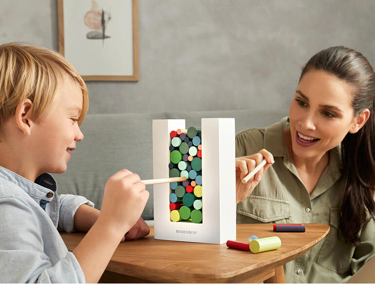Un enfant et un adulte jouent ensemble avec le jeu de dextérité Woodman à une table.