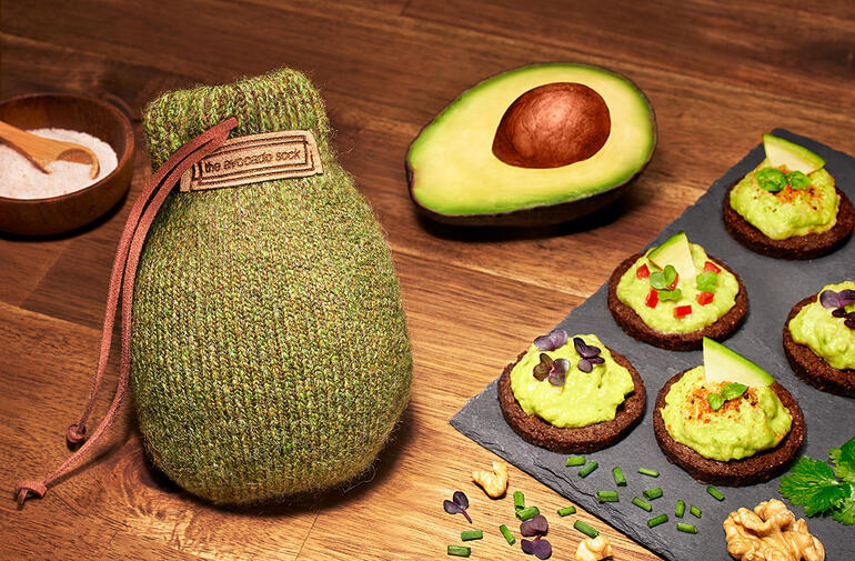 Avocado Sock® avec un avocat et des collations sur une table en bois.